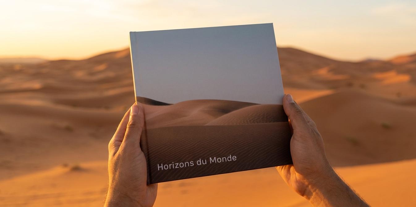 A printed Memoir album with a dune cover, held up in the desert